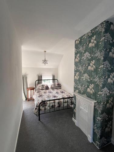 a bedroom with a bed and a green and white wallpaper at Fiddlers Cottage in Springmount