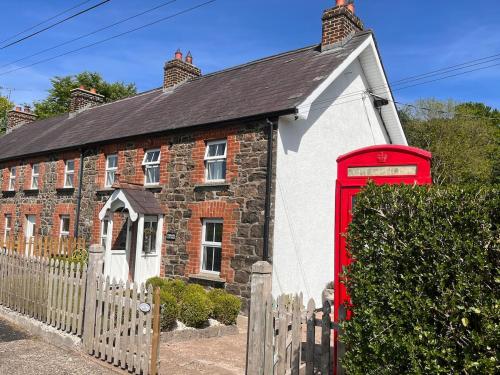 ein altes Backsteinhaus mit einer roten Telefonzelle in der Unterkunft Fiddlers Cottage in Springmount