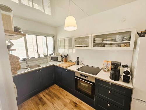 La cuisine est équipée de placards bleus, d'un évier et d'un réfrigérateur. dans l'établissement Bel appartement 3 couchages, climatisé, WIFI, vue mer, tout à pied, à Saint-Mandrier-sur-Mer