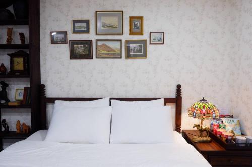 a bedroom with a white bed and pictures on the wall at The Rustic Home - Nguyên căn in Ho Chi Minh City