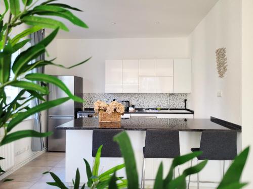 a kitchen with white cabinets and black counter tops at Hafenromantik pur - Exklusive Ferienwohnung mit erstklassigem Blick von "Momentic" in Neustadt in Holstein