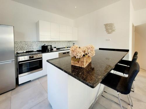 a kitchen with white cabinets and a black counter top at Hafenromantik pur - Exklusive Ferienwohnung mit erstklassigem Blick von "Momentic" in Neustadt in Holstein
