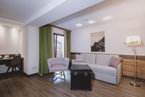 a living room with a couch and a desk at Hotel DIE SONNE in Saalbach Hinterglemm