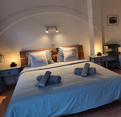 a large white bed with two blue pillows on it at Casa Monki in Raposeira