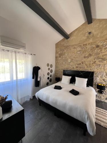 - une chambre avec un grand lit blanc et un mur en pierre dans l'établissement Le Domaine du Grand Cru, à Vagnas