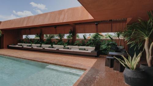 a resort with a swimming pool with benches and plants at Further Hotel in Canggu