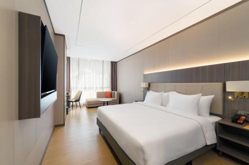 a hotel room with a large bed and a television at HARRIS Hotel & Suites Nagoya Batam in Nagoya