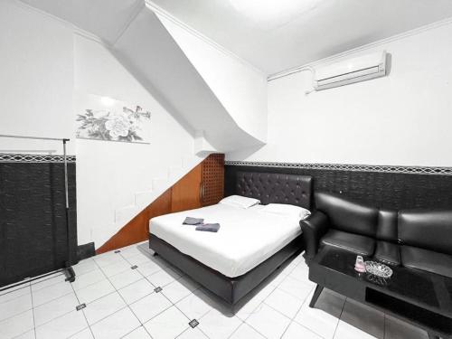 a bedroom with a bed and a black leather couch at Modom Residence in Jakarta