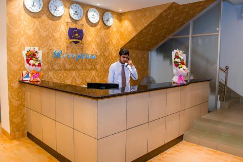 a man talking on a phone at a reception counter at Laurel Hotel Lake View in Dhaka