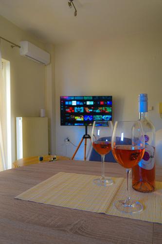 two glasses of wine sitting on a table with a television at Casa Dio in Preveza