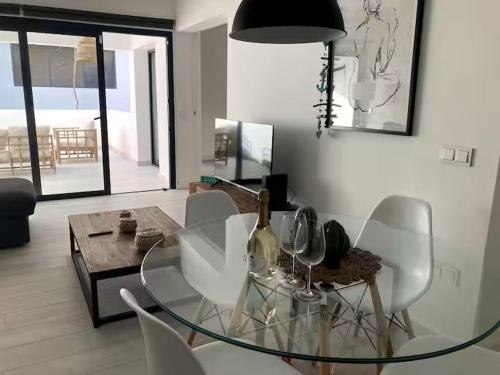 a dining room with a glass table and white chairs at La Sal - Apartment in Casilla de Costa in Villaverde