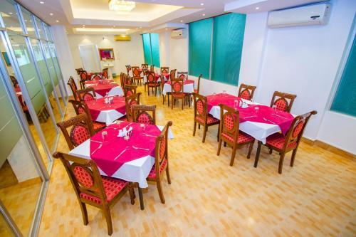 a dining room with tables and chairs with pink napkins at Laurel Hotel Lake View in Dhaka