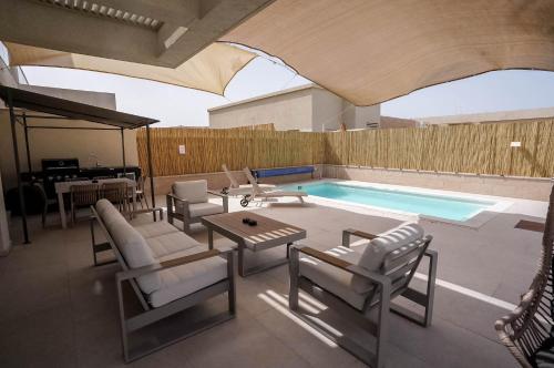a patio with chairs and a swimming pool at YalaRent Eilat Villa 4BR Private Pool & Garden in Eilat