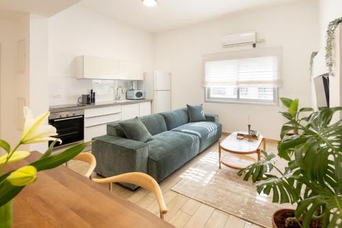 a living room with a green couch and a kitchen at Stylish 3BR Apt w Balcony 5 min Walk from Beach with Shelter by Sea N' Rent in Tel Aviv