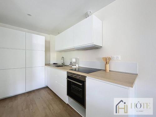 une cuisine avec des armoires blanches et un comptoir dans l'établissement Le Nid Moderne - Spacieux 2 Ch, à Dunkerque