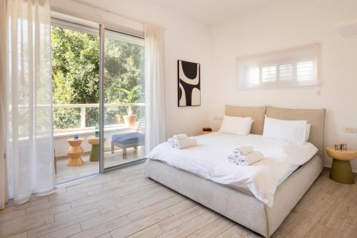 a bedroom with a large bed and a large window at Stylish 3BR Apt w Balcony 5 min Walk from Beach with Shelter by Sea N' Rent in Tel Aviv