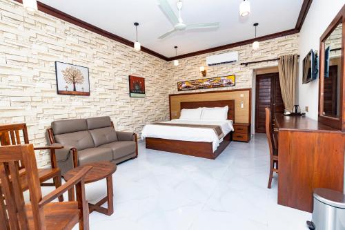 a bedroom with a bed and a couch and a desk at JKAB Lagoon Resort in Walauttu