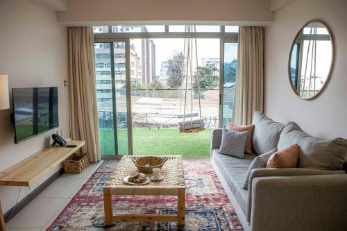 a living room with a couch and a tv at The Skies by YourHost Nairobi in Nairobi
