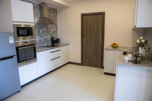 a kitchen with white appliances and a brown door at The Skies by YourHost Nairobi in Nairobi