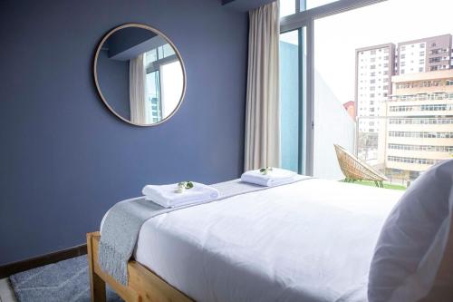 Un dormitorio con una cama y un espejo y una ventana. en The Skies by YourHost Nairobi, en Nairobi