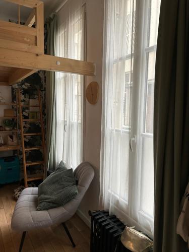 une pièce avec une chaise et une grande fenêtre dans l'établissement Studio à 2 pas du Moulin Rouge, à Paris
