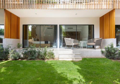 a house with a green lawn in the yard at Las Gaviotas Suites Hotel & Spa in Playa de Muro