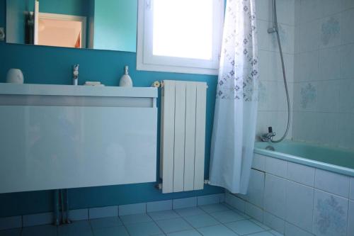 La salle de bains est pourvue d'un rideau de douche blanc et d'une baignoire. dans l'établissement Mais 3 pièces AYTRE - LR000-029, à Aytré