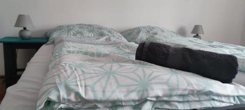 an unmade bed in a bedroom with a table at Kossuth Apartman in Hidasnémeti