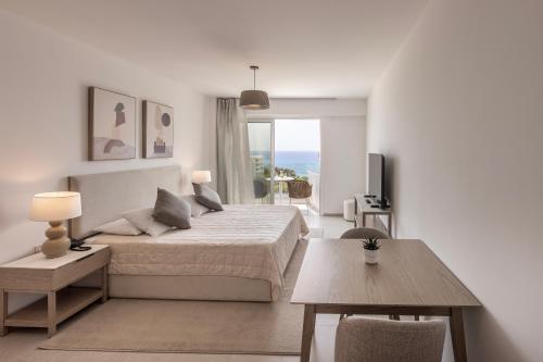 a white bedroom with a bed and a table at Cyprotel Florida in Ayia Napa