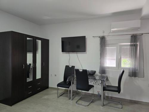 a room with a table and chairs and a television at SunSea Studio Apartment in Ðenovići