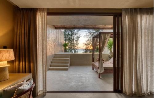 a room with a door leading to a bathroom with a tub at Café del Mar Phuket - Suite & Penthouse in Kamala Beach
