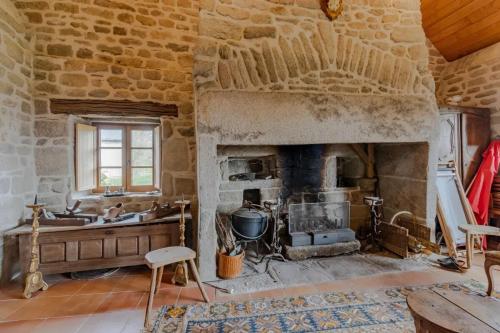 - un salon avec une cheminée dans un bâtiment en pierre dans l'établissement Maison authentique en granit - Chaumeil - Cheminée, à Chaumeil