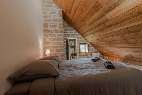 - un grand lit dans une chambre dotée d'un mur en pierre dans l'établissement Maison authentique en granit - Chaumeil - Cheminée, à Chaumeil