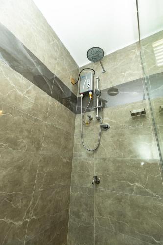 a bathroom with a shower with a glass door at JKAB Lagoon Resort in Walauttu