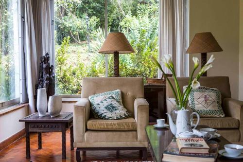 a living room with two chairs and a large window at Beautiful Historic House by YourHost Nairobi in Nairobi
