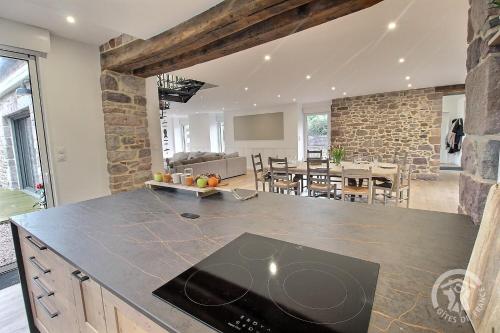 a kitchen and dining room with a stone wall at La maison de oueval in Frehel
