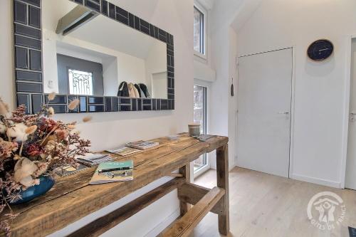 a room with a wooden table and a mirror at La maison de oueval in Frehel