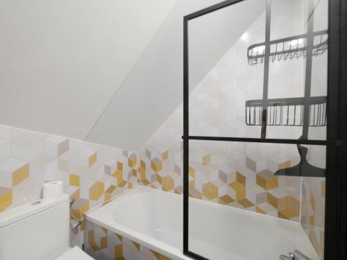 La salle de bains est pourvue d'une baignoire et d'une porte de douche en verre. dans l'établissement LE CHAMP MICHEL - appartement lumineux et cosy, à Chevaigné