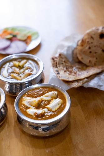 a table topped with bowls of soup and a plate of food at Hotel Pravasa Stay in Vadodara