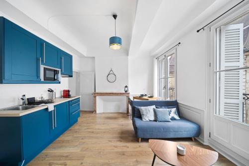 une cuisine avec des placards bleus et un canapé bleu dans l'établissement Confort & Calme - Appartement Centre Historique - Tout équipé, à Dijon