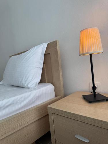 a bed with a white pillow and a lamp on a table at Emy's Rooms in Himare