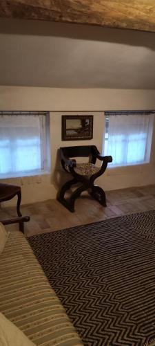 a living room with a chair and two windows at Lacetoliera Residenza d'epoca in Bosco Marengo