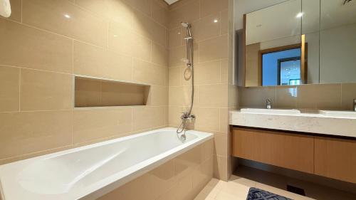 a bathroom with a tub and a sink and a mirror at Premium 2 Bedroom Creek Horizon in Dubai