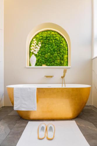 a bathroom with a tub with a window and two shoes at Above Hotels in Burnley
