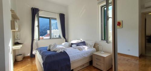 a bedroom with a bed with white sheets and a window at The Seaside Gem in Donji Morinj