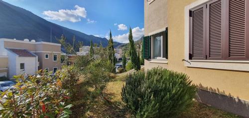 a view of a house with bushes and a mountain at The Seaside Gem in Donji Morinj