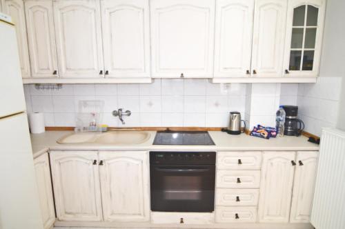 a kitchen with white cabinets and a sink at Metropolis Midtown in Kastoria