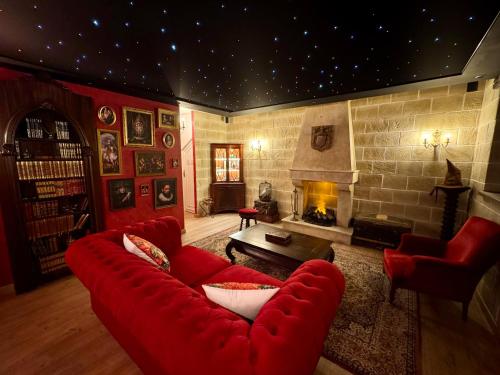 a living room with a red couch and a fireplace at Le Cocon du Sorcier in Fougères