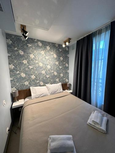 - une chambre avec un grand lit et du papier peint floral dans l'établissement MULTIRESIDENCE L'ELYSEE Paris, à Paris