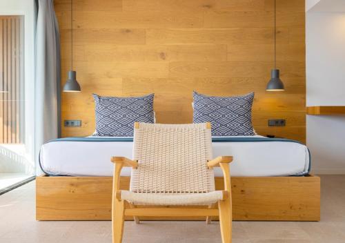 a bedroom with a bed and a rattan chair at Las Gaviotas Suites Hotel & Spa in Playa de Muro